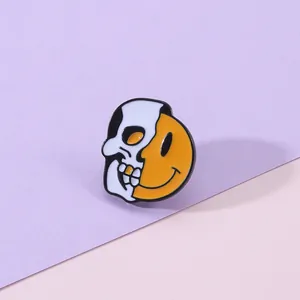 Vue détaillée d'un pin's en émail avec un demi-crâne et un demi-visage souriant jaune