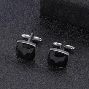 Macro shot of silver cufflinks with black sandstone inlay and bat logo detail