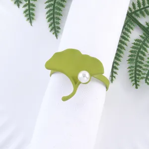 Servilletero de hoja de ginkgo verde con perla blanca sobre servilleta, vintage