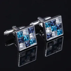 Square silver cufflinks for men with blue and white crystals on black surface