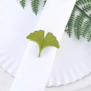 Servilletero de hoja de ginkgo verde con perla sobre servilleta blanca decorativa