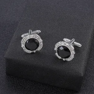 Detail shot of silver cufflinks featuring black faceted stone and crystal halo on black box