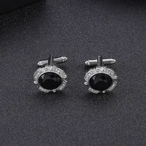 Macro detail of silver cufflinks with black round stone and crystal halo on leather background