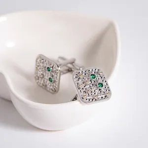 Boutons de manchette carrés argentés avec cristal vert et texture sur plat coeur