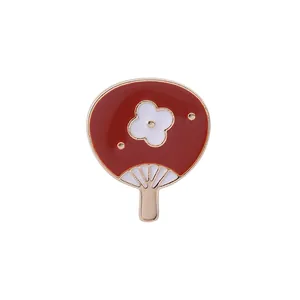 Détails d'une broche en forme d'éventail rouge et blanc avec des bords en alliage doré