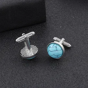 Detail of silver round cufflinks with turquoise stone inlay on black textured background