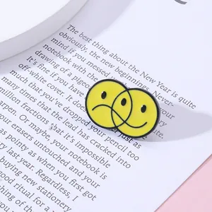 Détail d'un badge en émail avec visage triste et souriant sur fond de livre ancien