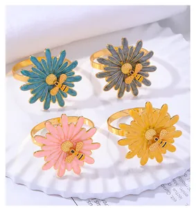Detail of four colorful daisy and bee napkin rings with gold finish on a white plate