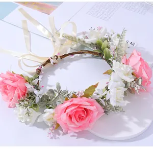 Nahaufnahme von rosa und weißen Kunstrosen auf einem geflochtenen Blumenkranz mit Band