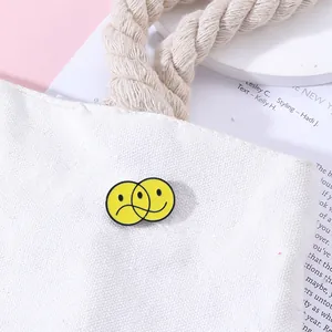 Détail macro d'une broche smiley en émail jaune épinglée sur un sac en toile blanc