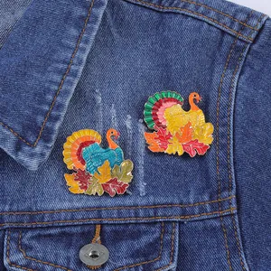 Squisite spille in smalto a forma di tacchino con foglie d'acero su una giacca di denim blu