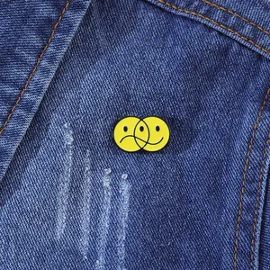 Détail d'épingles en émail jaune souriant et triste sur le tissu d'une veste en jean