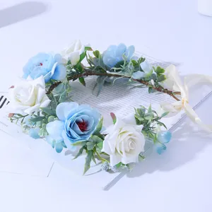 Couronne de fleurs avec roses bleu clair et blanches et feuilles vertes sur base de rotin