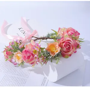 Détail d'une couronne de roses roses et orange avec ruban satin et feuilles vertes
