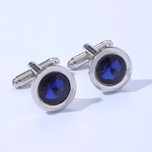Macro shot of round silver cufflinks with faceted deep blue gemstone and T-bar closure