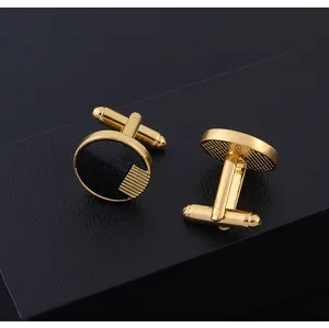 Détail de boutons de manchette ronds noir et or avec fermoir sur une boîte texturée