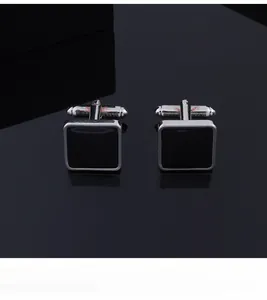 Macro shot of silver square cufflinks with black mirror finish on reflective surface
