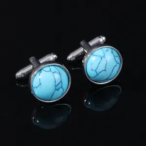 Macro detail of silver round cufflinks with turquoise marble stone inlay on black background