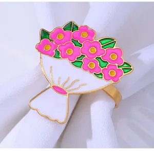 Vista macro de servilletero dorado con flores de esmalte rosa y hojas verdes