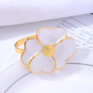 Golden flower napkin ring with white petals and marble texture on white plate