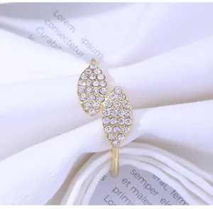 Detailed close-up of golden twin-leaf napkin ring inlaid with sparkling white rhinestones