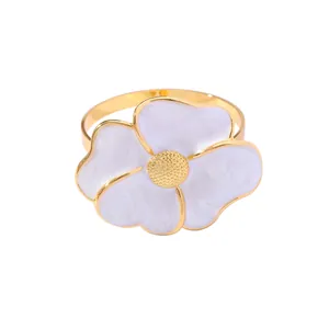 Golden flower napkin ring featuring white enamel petals and textured metallic center