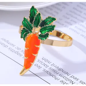 Close-up of carrot-shaped napkin ring with vibrant orange and green enamel on a gold base