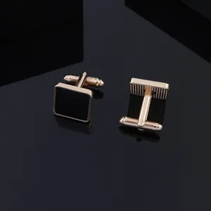 Elegant square gold plated cufflinks with black enamel inlay on a reflective surface