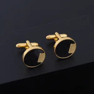 Boutons de manchette dorés ronds avec incrustation noire dans une boîte cadeau chic