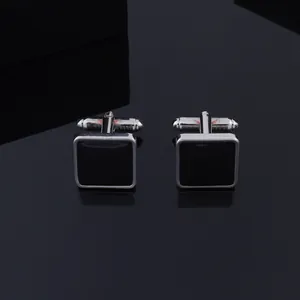 Minimalist square black cufflinks with silver metal frames on a reflective surface