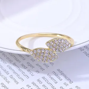 Golden double-leaf napkin ring set with small white crystals on a white ceramic plate