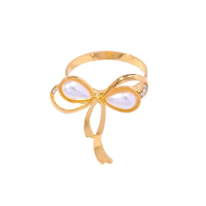 Eleganter goldener Serviettenring mit Schleife, Tropfenperlen und Strass auf weißem Grund