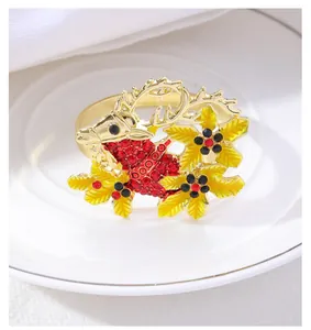 Close-up of a golden Christmas reindeer napkin ring with red rhinestones on a white plate