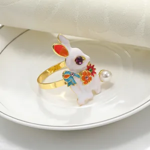Elegante servilletero de conejo dorado con detalles de esmalte y perla sobre plato blanco