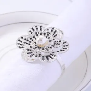 Silver flower napkin ring with black rhinestones and pearl on white cotton napkin