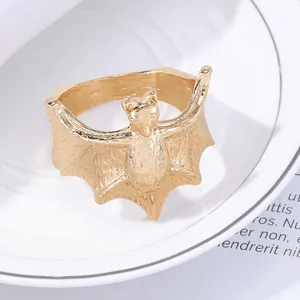 Macro detail of a golden bat napkin ring with embossed texture on a white plate