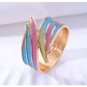 Makroaufnahme eines goldenen Wellenrings mit bunten Glitzerstreifen und poliertem Finish