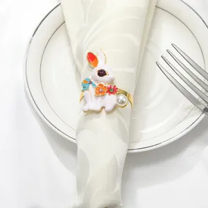 Detalle de servilletero de conejo en esmalte blanco con flores y perla en tela beige