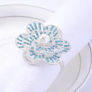 Elegant floral napkin ring with blue rhinestones and pearl on white linen napkin