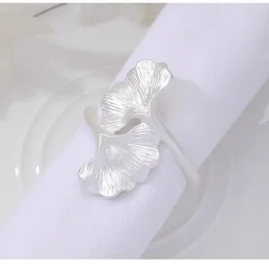 Close-up of silver ginkgo leaf napkin ring with detailed texture on a white cloth