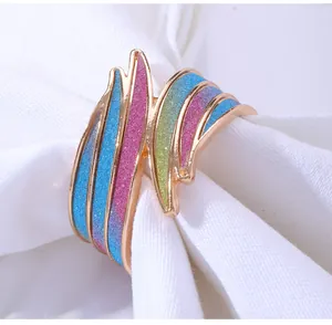 Detail von Regenbogen-Glitzer-Serviettenring mit goldenem Wellendesign auf weißem Tuch