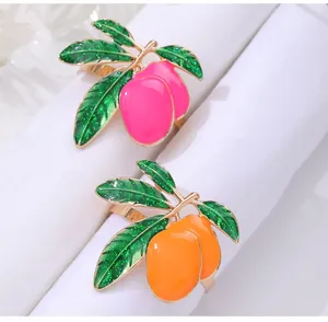 Detailed macro of mango napkin rings in pink and orange enamel on gold alloy