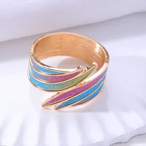 Mehrlagiger Goldring in Federform mit bunten Glitzerstreifen in Blau, Rosa und Lila