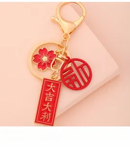 Detailed close-up of golden keychain featuring red floral and lucky charm pendants