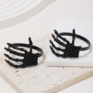 Detalle de dos servilleteros de mano de esqueleto negro brillante sobre piedra