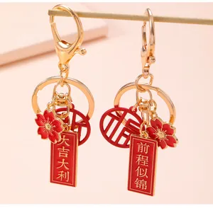 Close-up of gold Chinese character keychains with red enamel flower and lucky charms