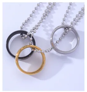 Drei minimalistische Ringe aus Edelstahl in Schwarz, Gold und Silber an einer Perlenkette