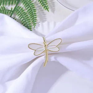 Elegant gold dragonfly napkin ring with white enamel wings on a folded white napkin