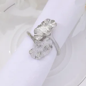 Elegant silver ginkgo leaf napkin ring with detailed metallic texture on white plate