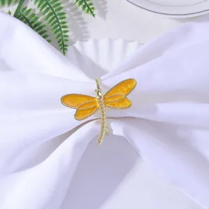 Macro detail of a dragonfly napkin ring with orange enamel wings on a white cloth